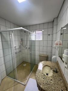 a bathroom with a sink and a glass shower at Hoteis Cattoni Executive in Lages