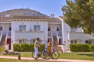 a man and woman walking their bikes in front of a building at Seaclub Alcudia in Port d'Alcudia
