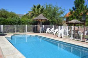 a swimming pool with a fence and some chairs at Cabañas Quilquelen in Merlo