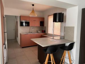 a kitchen with a counter and two bar stools at appartement cosy in Nîmes