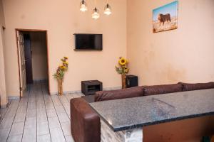 a living room with a couch and a tv at Falcon Lodge PK in Bela-Bela