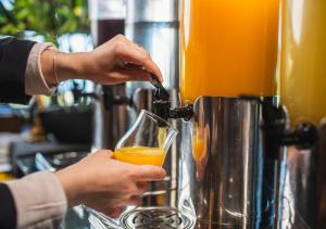 a person is holding a glass of orange juice at Villa del Rio Express in Valdivia
