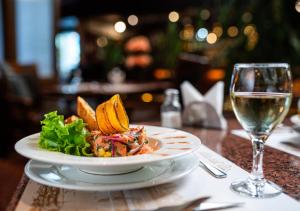 a plate of food on a table with a glass of wine at Villa del Rio Express in Valdivia
