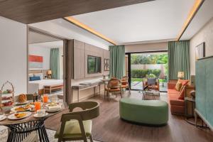 a living room with a green chair and a room with a bed at Taj Alibaug Resort & Spa, Maharashtra in Alibaug