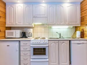 a white kitchen with white appliances and wooden cabinets at Holiday Home Revontuli by Interhome in Ruka +9 photos