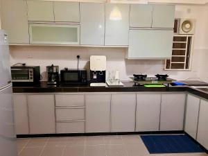 a kitchen with white cabinets and white appliances at AmyHana Cozynest in Putrajaya
