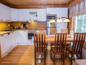 a kitchen with white cabinets and a wooden table with chairs at Holiday Home Joutilas by Interhome in Ruka +12 photos
