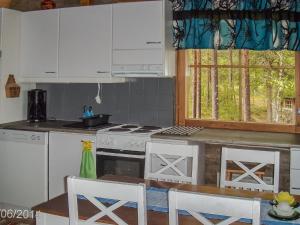 a kitchen with a stove and a table with chairs at Holiday Home Honkapirtti- vuotunki by Interhome in Kunnari