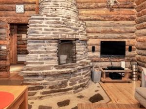 a living room with a stone fireplace in a log cabin at Holiday Home Rantaruka 4d1 by Interhome in Ruka