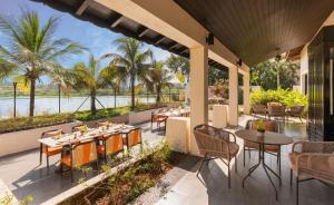 an outdoor patio with tables and chairs and a view of the water at Taj Alibaug Resort & Spa, Maharashtra in Alibaug