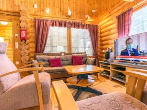 a living room with a couch and a tv at Holiday Home Keisarintupa by Interhome in Ruka +7 photos