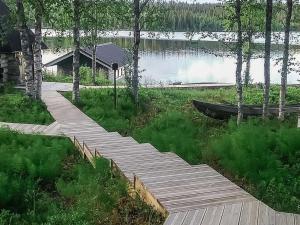 a wooden walkway next to a lake with a boat at Holiday Home Kallentupa by Interhome in Ruka