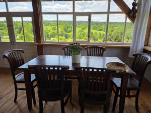 a wooden table and chairs in a room with windows at Utopia Dom przy winnicy in Nowica
