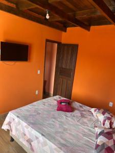 a bedroom with a large bed with an orange wall at casa passos e reis in Corumbau