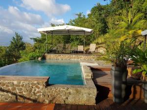 a swimming pool with an umbrella and a table at Villa THEOROM in Chambort
