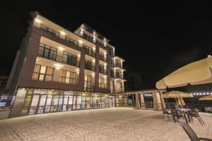 a large building with chairs and an umbrella at night at Nabada Hotel - Riverside in Ozurgetʼi