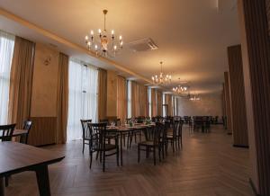 a dining room with tables and chairs and a chandelier at Nabada Hotel - Riverside in Ozurgetʼi