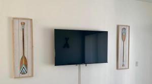 a flat screen tv on a wall with two mirrors at Oceans Beach Resort 735 in Deerfield Beach