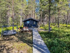 a blue cabin in the woods with a wooden walkway at Holiday Home Kitkaranta by Interhome in Kitka