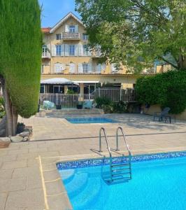 a swimming pool in front of a large building at HOTEL ST SEBASTIEN in Roquebillière