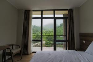 a bedroom with a bed and a large window at Nabada Hotel - Riverside in Ozurgetʼi