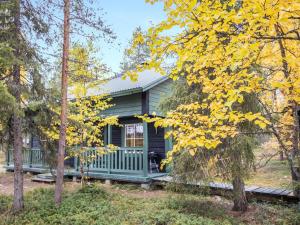 a green cabin with a porch in the woods at Holiday Home Suvantovirta by Interhome in Kaukonen