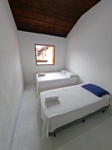 two beds in a small room with a window at CASA DE HOSPEDAGEM FLORES PARATY AMBIENTE FAMILIAR 600M do CENTRO in Paraty