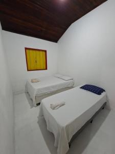 three beds in a white room with a wooden ceiling at CASA DE HOSPEDAGEM FLORES PARATY AMBIENTE FAMILIAR 600M do CENTRO in Paraty