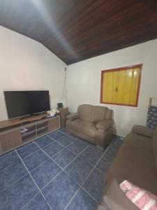 a living room with a couch and a flat screen tv at CASA DE HOSPEDAGEM FLORES PARATY AMBIENTE FAMILIAR 600M do CENTRO in Paraty