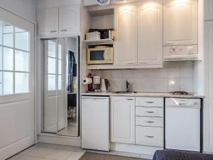 a white kitchen with white cabinets and a refrigerator at Holiday Home Levin tuisku by Interhome in Levi +9 photos