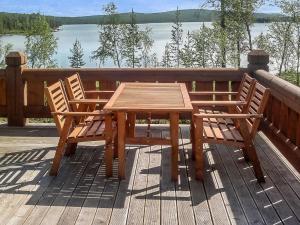 a wooden table and two chairs on a deck with a lake at Holiday Home Aamunkoi by Interhome in Veskoniemi