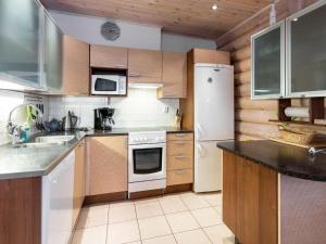 a kitchen with white appliances and wooden cabinets at Holiday Home Aspilevi by Interhome in Levi