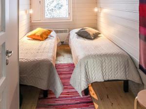 two beds in a small room with a window at Holiday Home Mukan maja by Interhome in Köngäs +5 photos