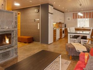 a living room with a fireplace and a kitchen at Holiday Home Jutapirtti by Interhome in Levi
