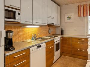 a kitchen with white appliances and wooden cabinets at Holiday Home Jutapirtti by Interhome in Levi +15 photos