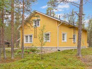 a yellow house in the woods with trees at Holiday Home Jutapirtti by Interhome in Levi