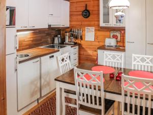 a kitchen with white cabinets and a table and chairs at Holiday Home Saikulevi by Interhome in Levi