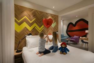 two children sitting on a bed with a heart wall at Cucu Hotel in Tel Aviv