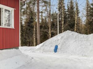 a pile of snow next to a red building with a blue shovel at Holiday Home Levin mummola by Interhome in Köngäs