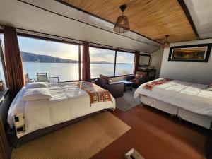 a bedroom with two beds and a view of the water at Titicaca island lodge peru in Puno