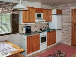 a kitchen with white appliances and wooden cabinets at Holiday Home Ahonlaita by Interhome in Karvonen +7 photos