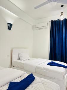 two beds in a room with a blue curtain at Happiness Guest House in Luxor +46 photos
