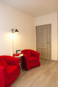 チュメニにあるСчастливая квартира на Зелинского 1のリビングルーム(赤い椅子2脚、テーブル付)