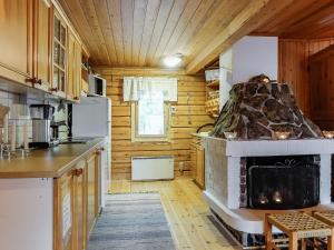 a kitchen with a fireplace in a log cabin at Holiday Home Piilola by Interhome in Raanujärvi