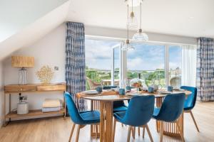 a dining room with a wooden table and blue chairs at Thurlestone Retreats in Thurlestone