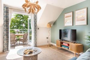 a living room with a tv and a table at Thurlestone Retreats in Thurlestone
