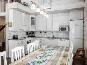 a kitchen with white cabinets and a table with chairs at Holiday Home Kerkänperä by Interhome in Luosto