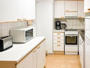 a kitchen with white cabinets and a microwave at Holiday Home Ylläskakkonen b9 by Interhome in Ylläsjärvi