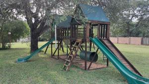 a wooden playground with a slide and a tree at Sand River Cottages in Hazyview