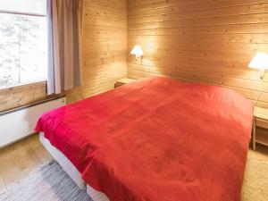 a bedroom with a red bed in a wooden room at Holiday Home Tunturinvieri k2 by Interhome in Ylläsjärvi